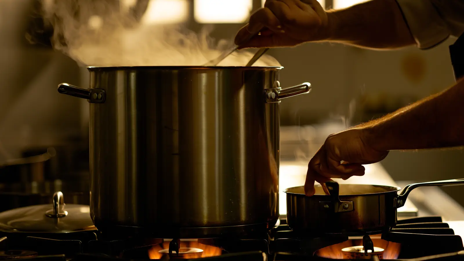 Ladling from a large stockpot beside a small saucepan